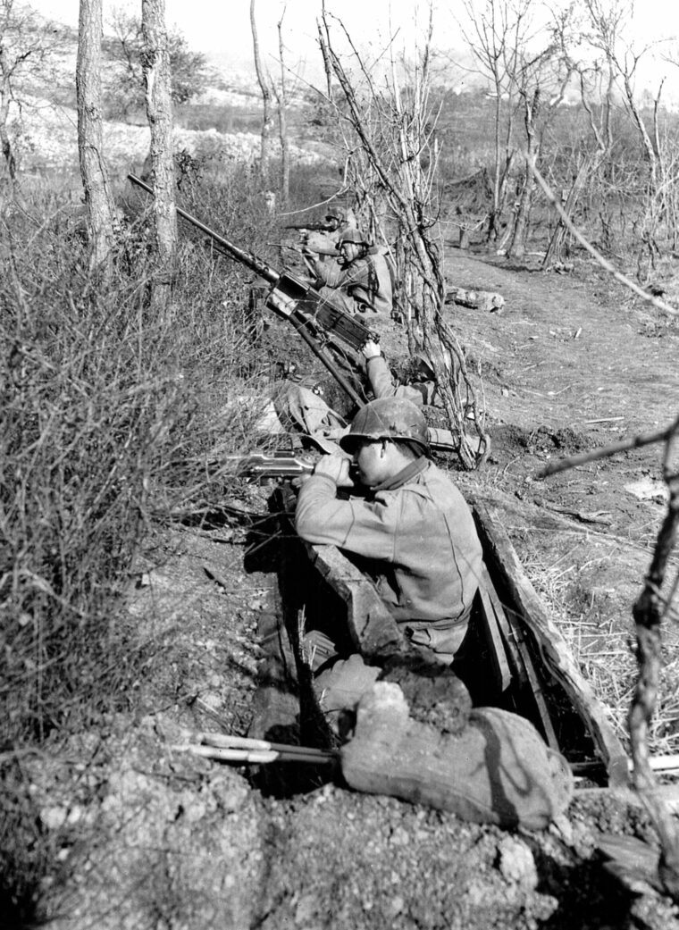 Near the banks of the Rapido River, American soldiers seek cover behind a thicket of brush and barbed wire on February 7, 1944. The ill-fated attempt by elements of the 36th Infantry Division to cross the Rapido was one of the war’s most regrettable tactical reverses.
