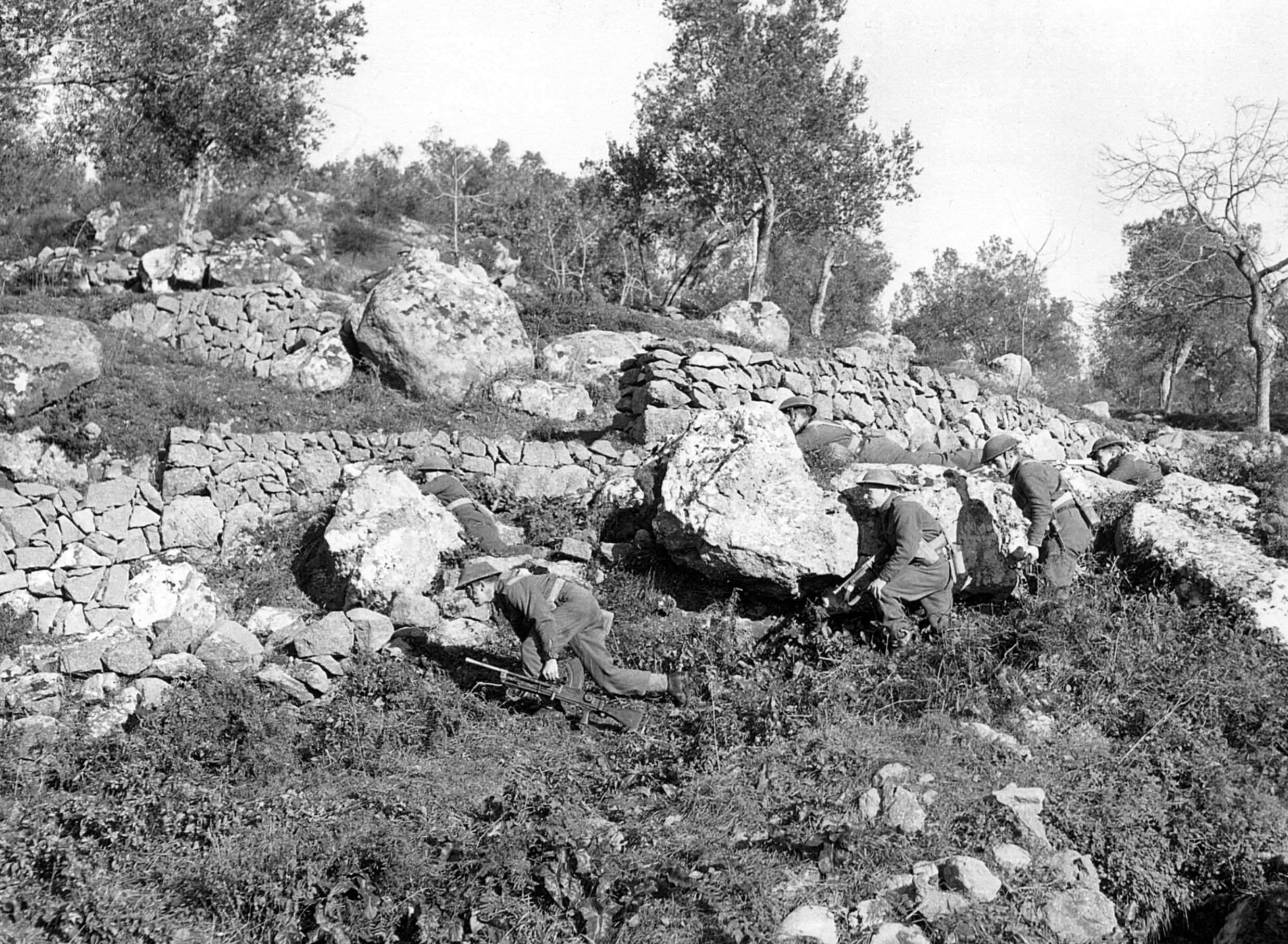 Carrying their standard-issue Bren guns, British soldiers use the cover of a stone wall to advance against German positions near the town of Cassino. The Allies eventually attempted four times to take the ruins of the Benedictine abbey above the town.