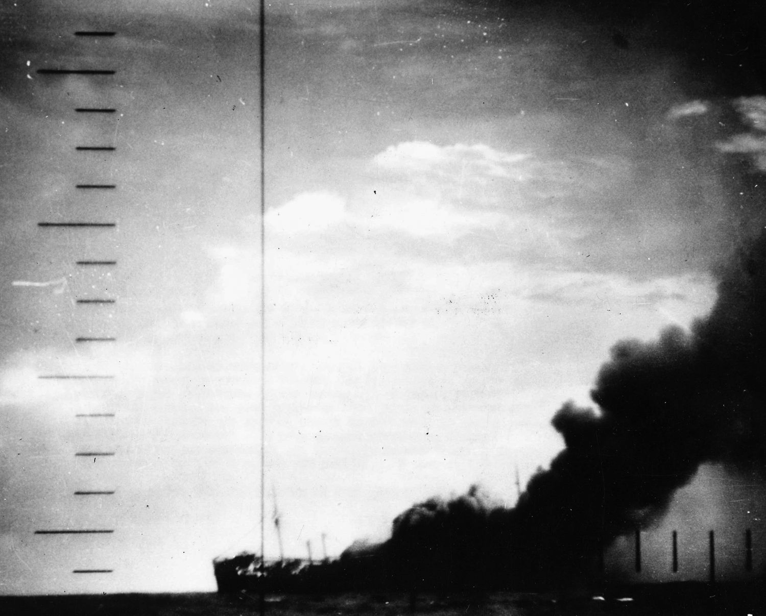 Seen through the periscope of the U.S. Navy submarine that has just successfully attacked it, a stricken Japanese warship lists to port and belches a heavy cloud of black smoke before plunging to the bottom of the Pacific Ocean.