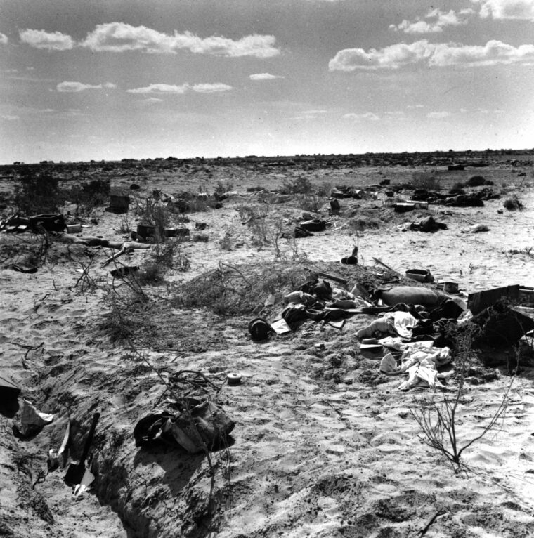 Dead Germans and their personal effects lie strewn across a scarred landscape following the capture of their position by British troops during the early stages of the Battle of El Alamein.