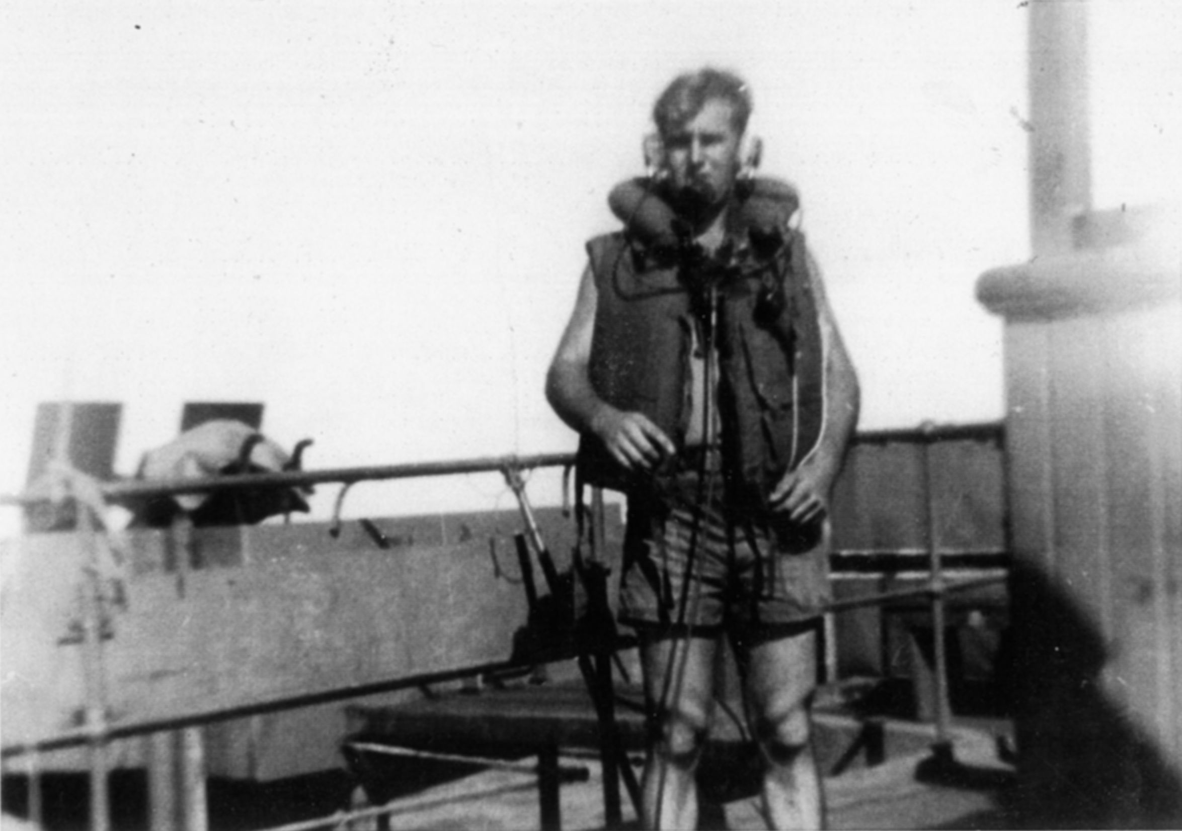 A combat-ready Naval Armed Guardsman is shown wearing his life vest and a radio headset used for communication between gun stations aboard his ship.