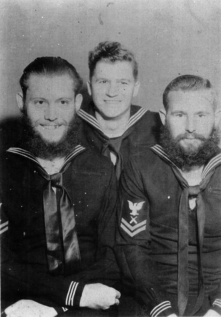 Three Naval Armed Guardsmen, their nonregulation hair and beards prominent, pose for a photo while on leave. Duty in the Armed Guard was acknowledged among the sailors as quite hazardous.