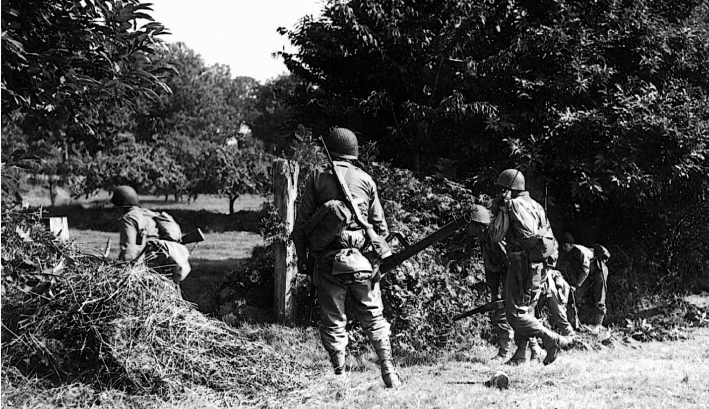 Cautiously moving through the Bocage, or hedgerow country, of France, infantrymen of the U.S. 30th Division advance toward Mortain where they made a heroic stand against a German counterattack.