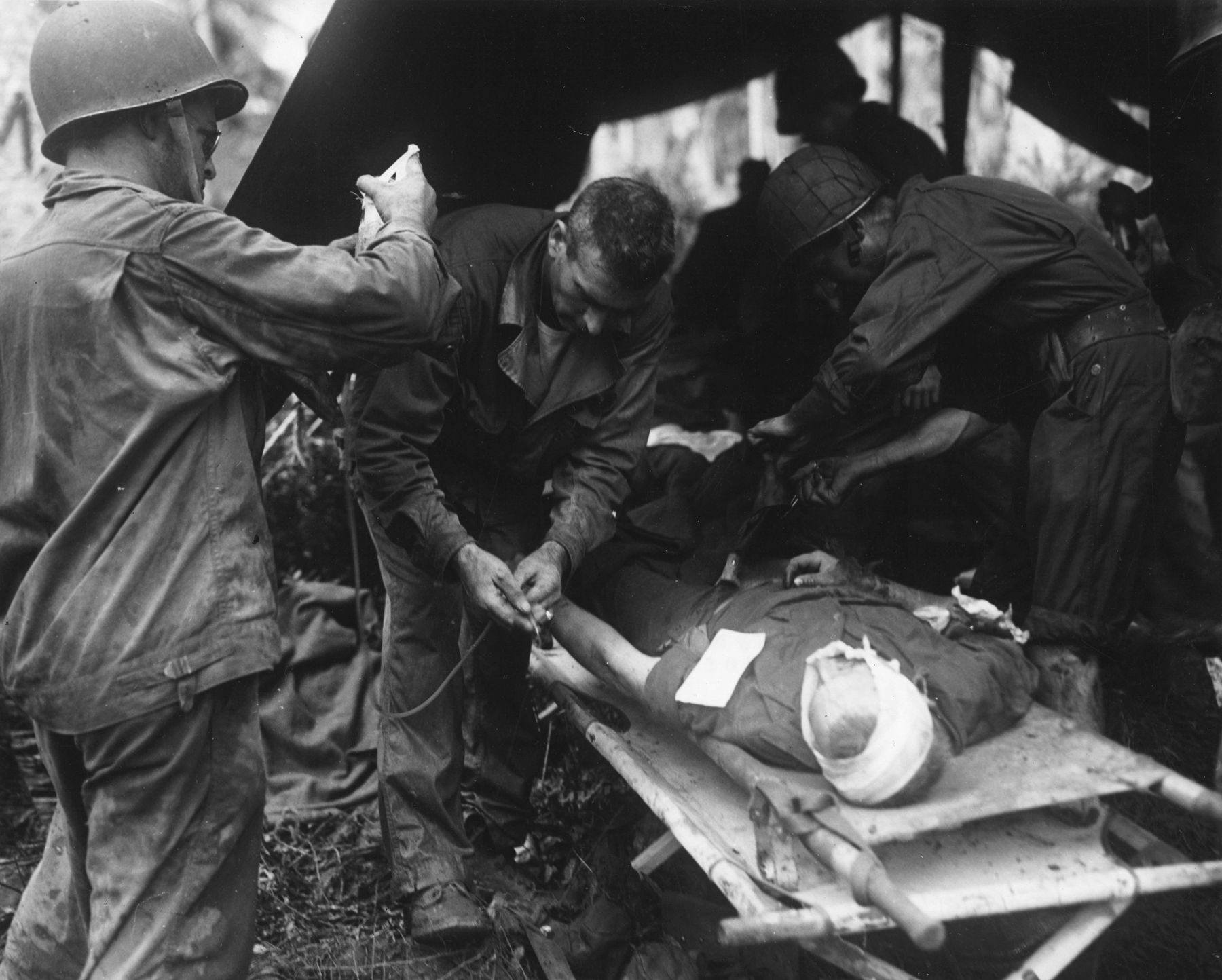 His head bandaged, a wounded Marine on the island of Rendova in the Solomons receives continuing care at an aid station near the front line.