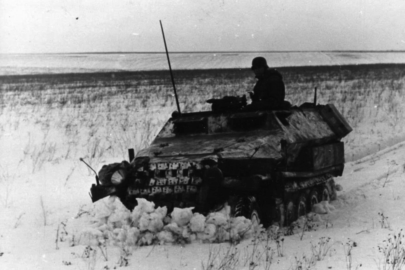 Battling the intense cold and winter weather as well as the invading Germans, a Soviet patrol and its armored half-track forge their way through a snowy field on the Russian steppe during the winter of 1942. 