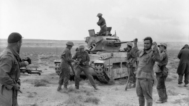 The German crew, which has manned a captured British Matilda tank in the Western Desert in 1941, surrenders to a group of New Zealand troops after the vehicle has been disabled by antitank fire. Note the German markings and flag draping the tank. (Australian War Memorial)