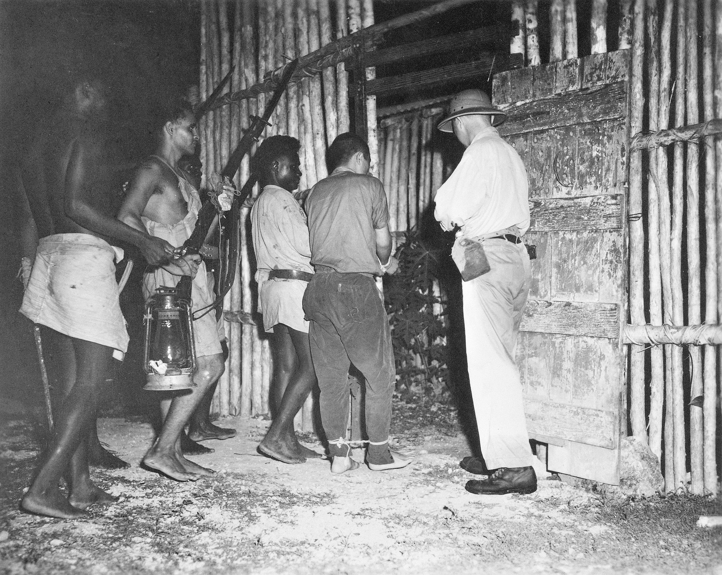 An armed guard of native scouts trained and commanded by Captain D.G. Kennedy escorts a captured Japanese pilot into captivity at the Segi coast watchers’ station on New Georgia in March 1943.