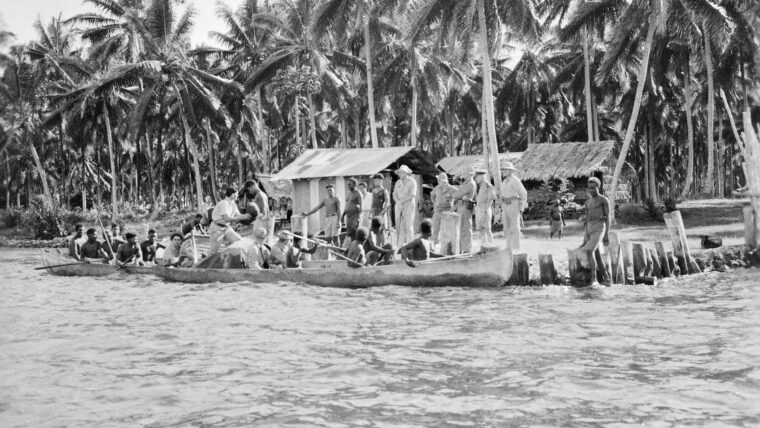A contingent of U.S. Marine Corps intelligence personnel and native scouts shove their canoes off from the coast watchers’ station at Segi, New Guinea, on a routine patrol.
