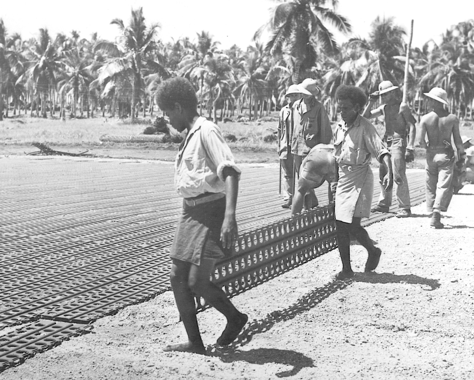 Native and American workers rush to complete the airfield the Japanese had begun to build at Lunga on Guadalcanal. Coast watchers had reported on Japanese progress in building the airfield, and from strategic points around the island warned of impending attacks on the area. The airfield was named Henderson Field.