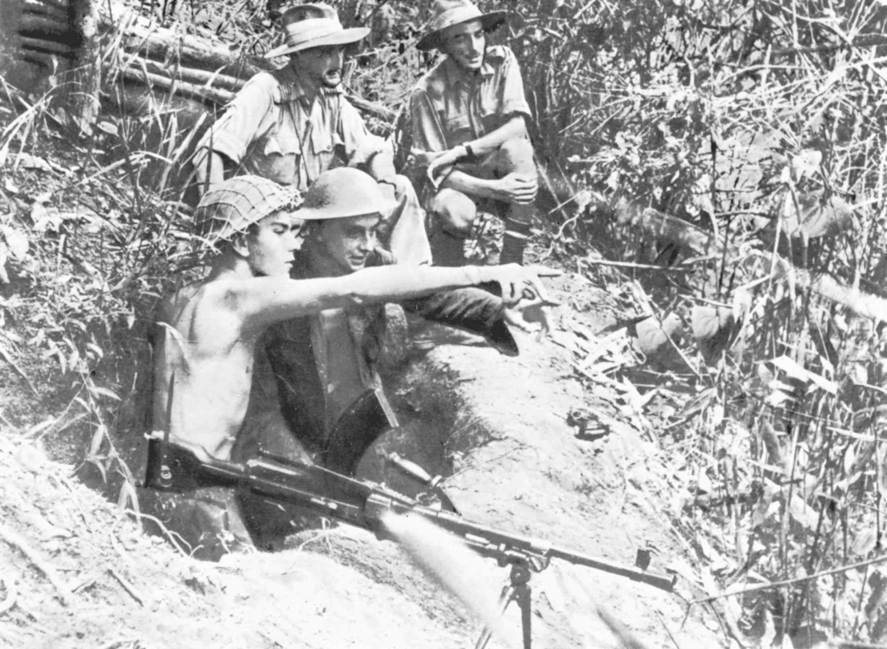 Positioned to command the high ground above an airfield in the Imphal Valley, a Bren gun team of RAF personnel spots movement in the distant jungle. 