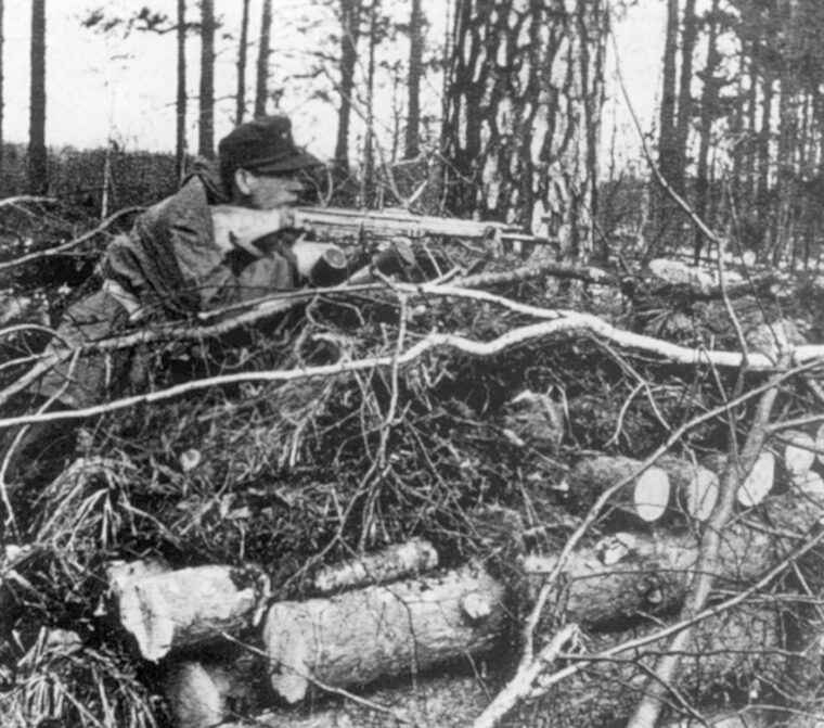 In action against the advancing Allies on the Western Front, a Waffen-SS soldier takes aim with a Sturmgewehr 44 assault rifle during the waning months or World War II.