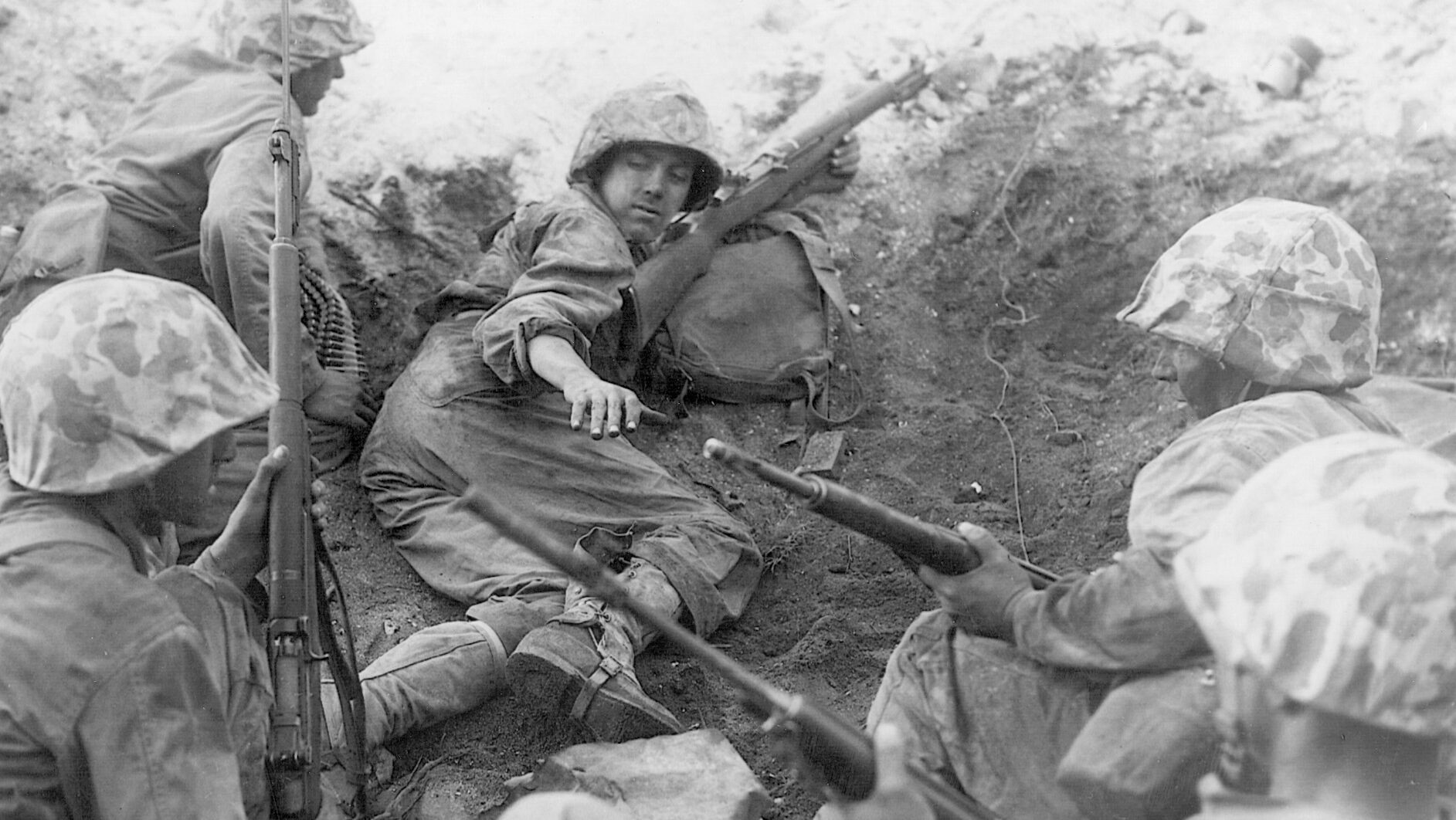 Marines taking shelter in a shell hole on Namur await the signal from their commander to advance toward Japanese positions.