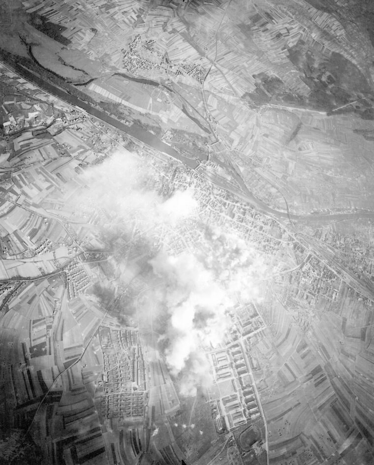 A pall of smoke rises from the manufacturing center of Schweinfurt as Eighth Air Force bombers deliver their payloads.