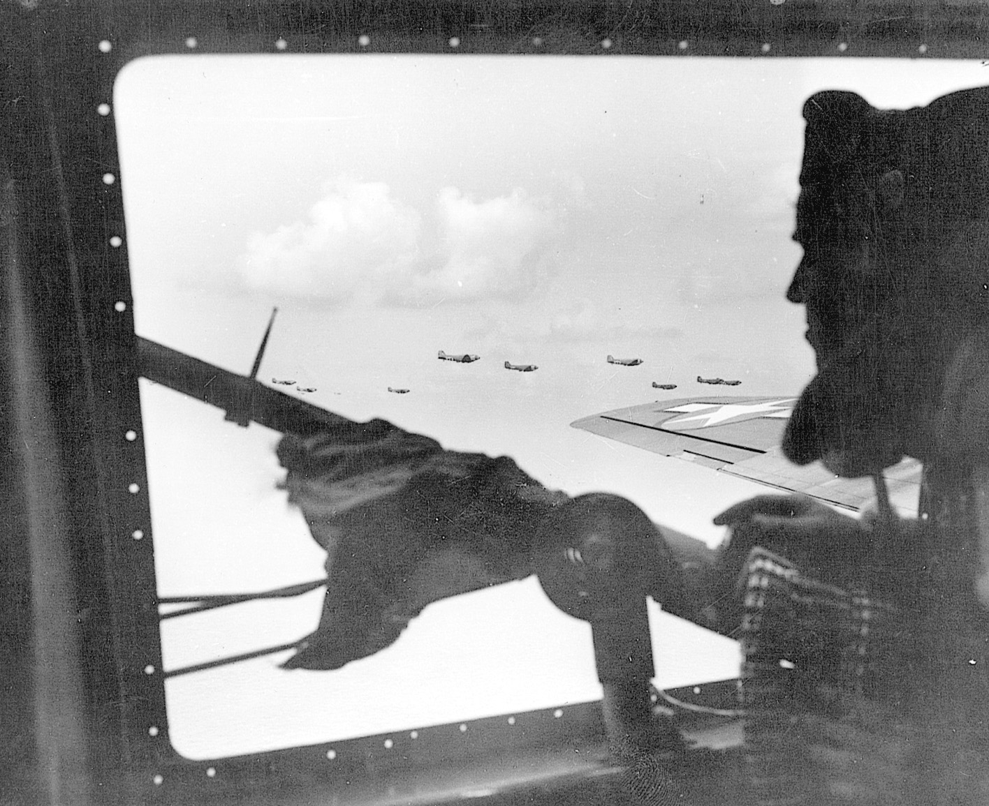 Peering from his gun position in an American bomber, an alert airman scans the sky for enemy fighter aircraft during a mission deep into Germany. 