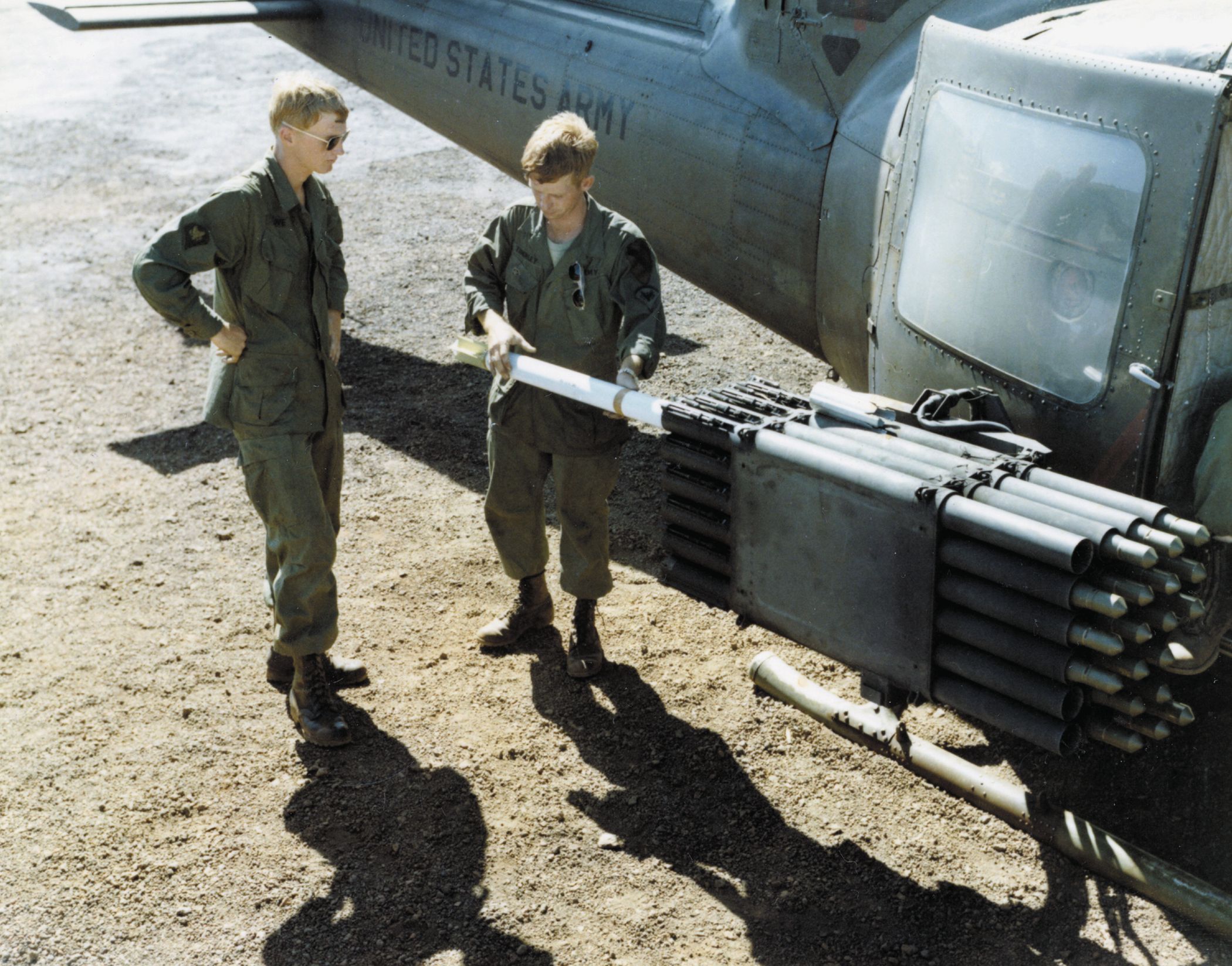 Crew Chief Eddie Townley of the 20th Artillery shows SP4 William Love the proper way to load and arm aerial rockets on a UH-1B in July 1967.
