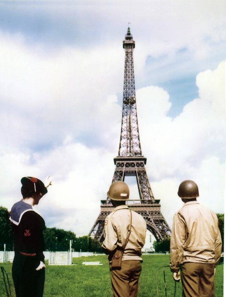 Accompanied by a French sailor, two American soldiers enjoy the view of the Eiffel Tower.