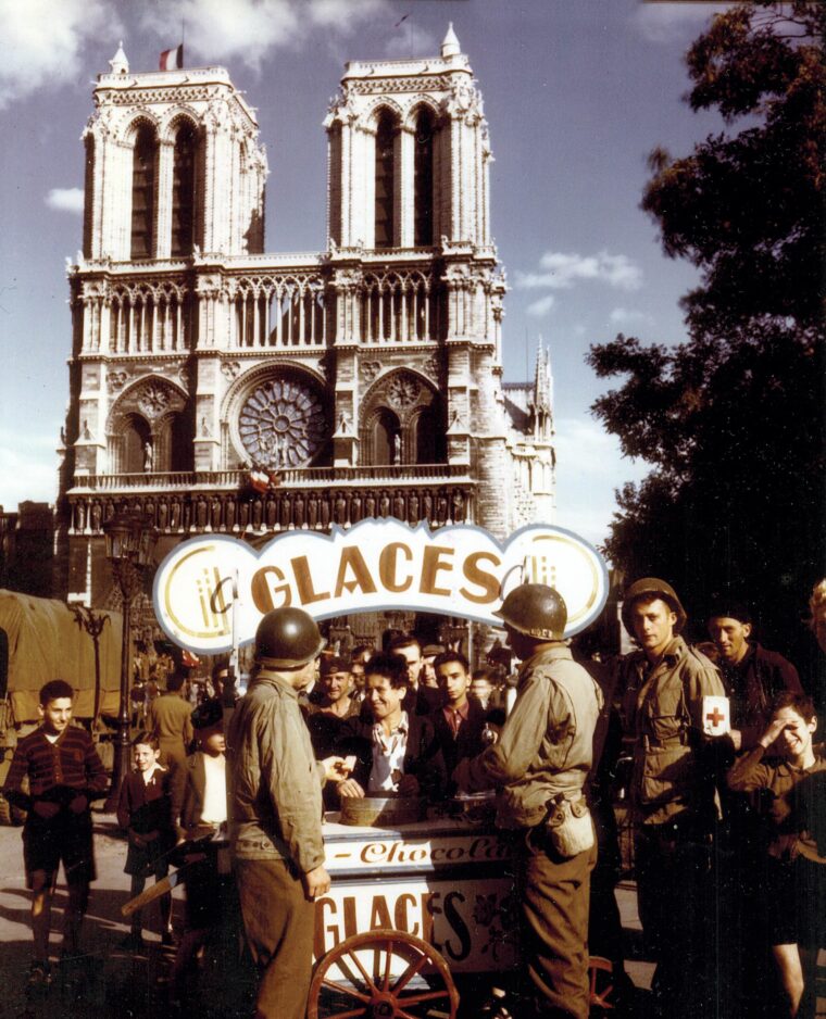 Two soldiers buy flavored ice in front of Notre Dame Cathedral.