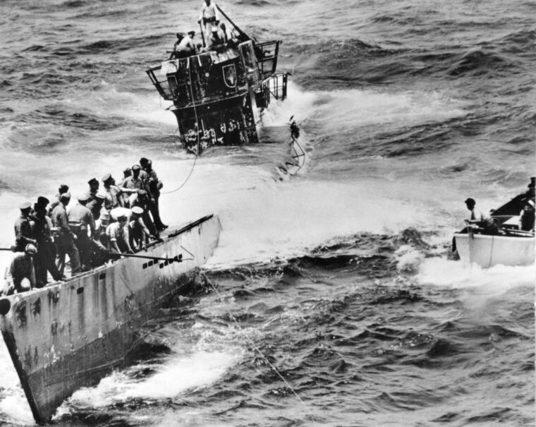 Taking on water, the U-505 is perilously close to sinking. A towline is delivered from a whaleboat to a boarding party so that the submarine may be taken to safety.