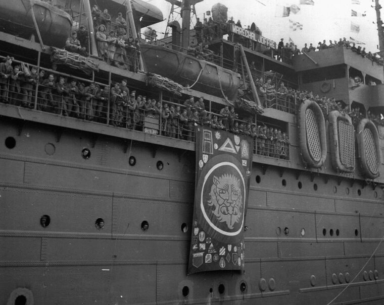 Members of the 106th Infantry Division crowd the rails of their troopship for their first glimpse of New York City and the United States.