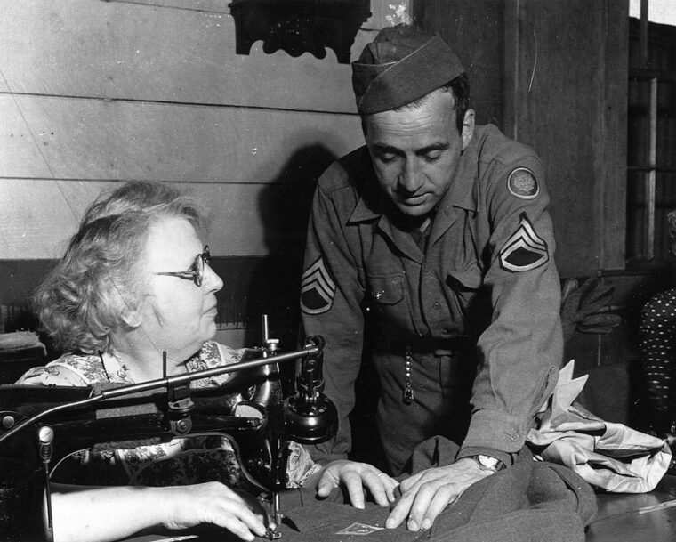 A Ruptured Duck—a gold discharge emblem—is sewn onto Faulkner’s blouse as he supervises the job.