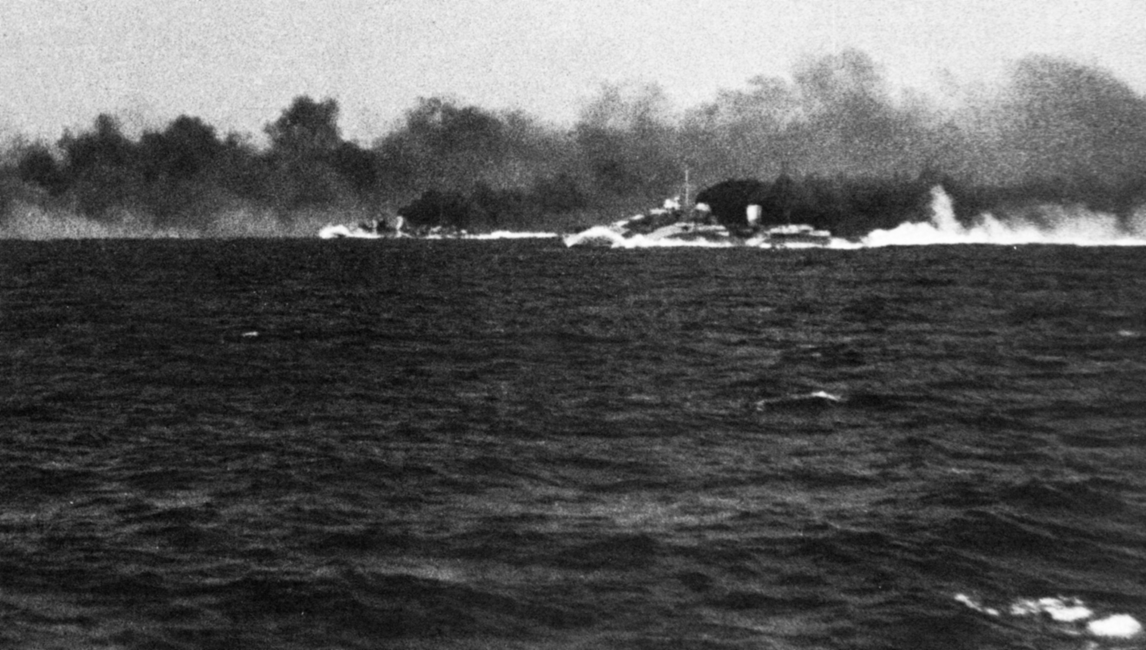 Prior to coming under attack itself, the British cruiser HMS Gloucester was unable to take advantage of a protective smokescreen seen belching in black and white clouds from the cruisers HMS Ajax and HMAS Perth.  In this photograph taken from the deck of the Gloucester, the other British warships are being fired upon by the Italian battleship Vittorio Veneto.