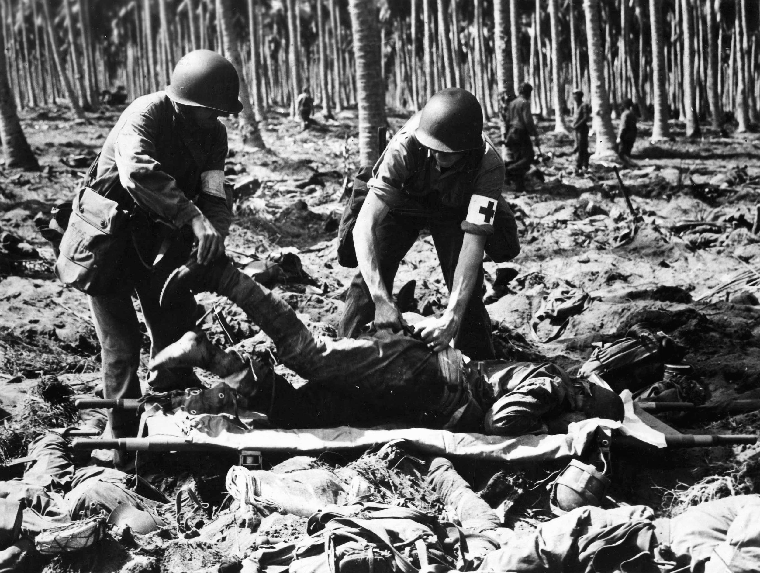 Placing a wounded Japanese soldier on a stretcher, two U.S. Marines have plucked the injured man from among the bodies of his dead comrades. The suicidal charge of the Ichiki Detachment at the Tenaru River took a heavy toll among the elite troops. 
