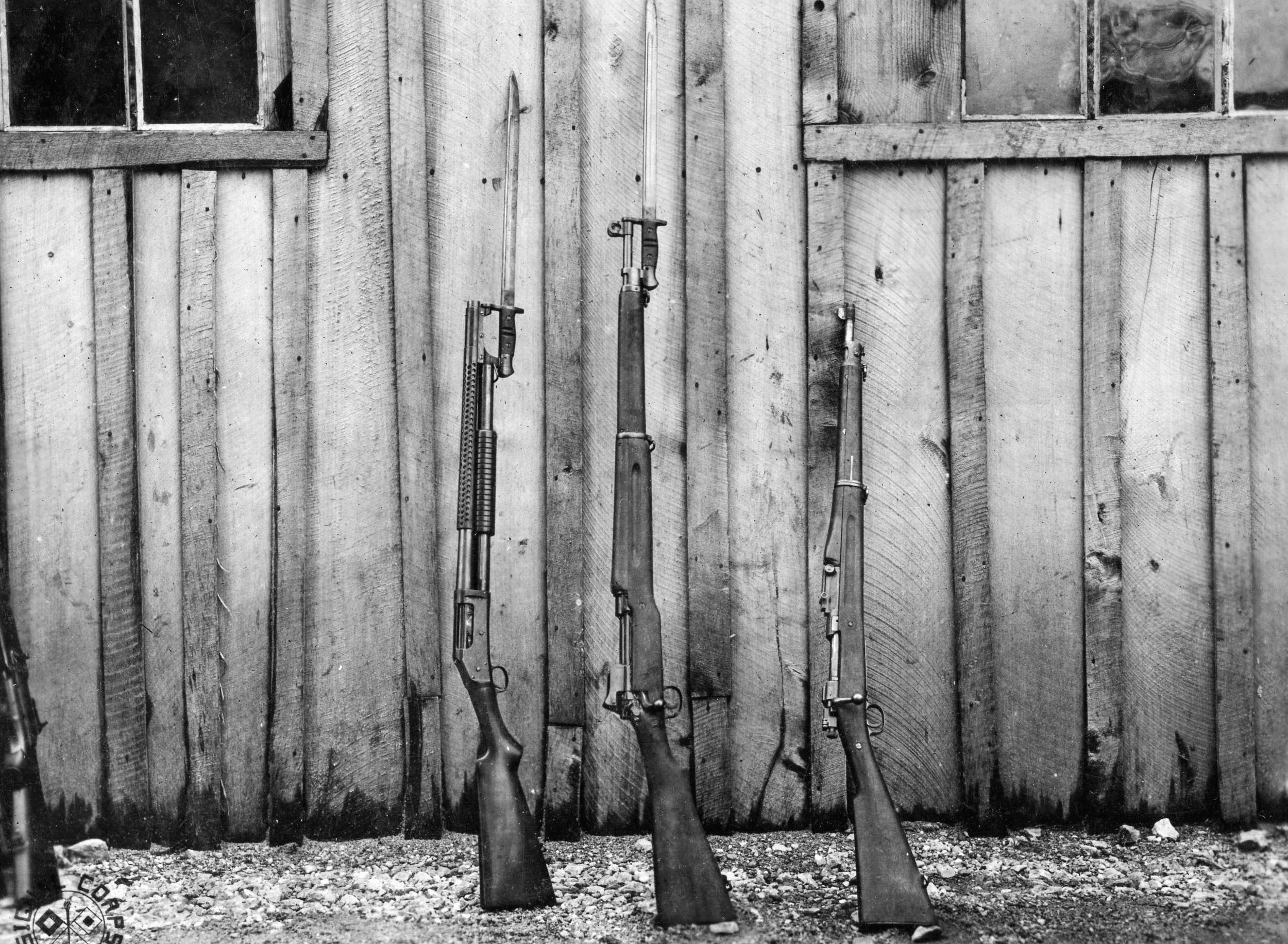 World War I-era arms, left to right, include the 12-gauge shotgun with bayonet attached, American Enfield, and Springfield rifles.