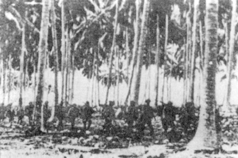 Making their way through a coconut grove, Japanese soldiers of the Kawaguchi Detachment move toward battle.