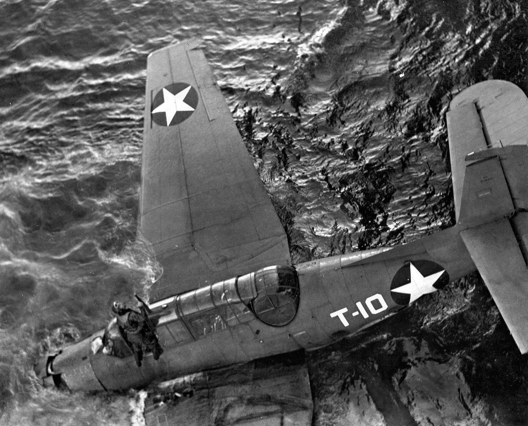 A student aviator emerges from the cockpit of his floating TBF Avenger torpedo bomber. The plane would soon succumb to the ocean. While Avengers held a crew of three, on training missions the aviators flew alone.