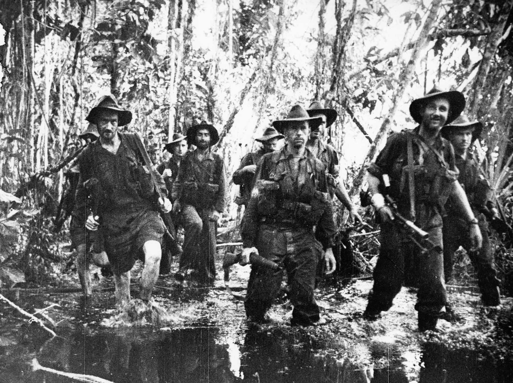 Australian troops slosh through knee-deep water in the jungles of Buna. The stifling heat and swampy, insect-infested terrain took a harsh toll on the morale of many.