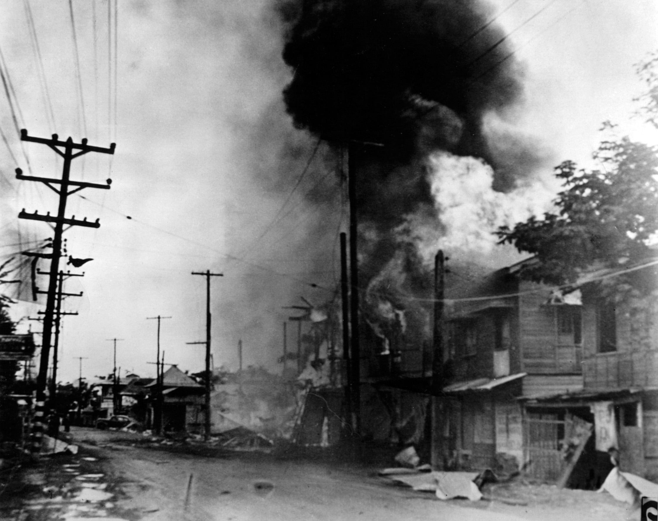 Charred and burning buildings line the streets in Manila shortly after a Japanese bombing raid.