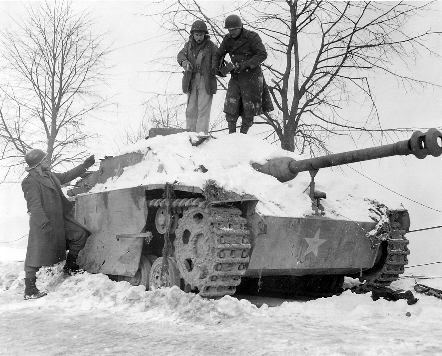Combat engineers attempt to remove an abandoned German tank. Disguised with  U.S. markings, this vehicle was probably used in the attack on Malmédy.