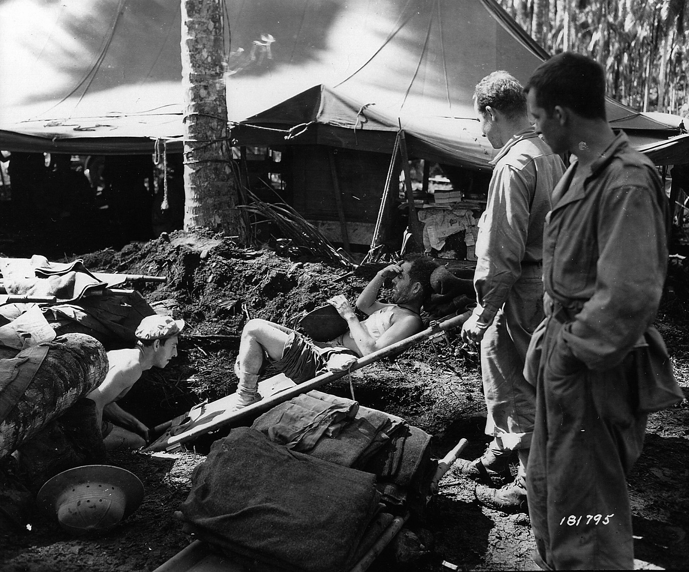 Wounded in action during Operation Cartwheel, a soldier of the 43rd Infantry Division is moved on a stretcher to the operating room at the division’s field hospital.  The advent of the field hospital in World War II saved the lives of many wounded American soldiers.