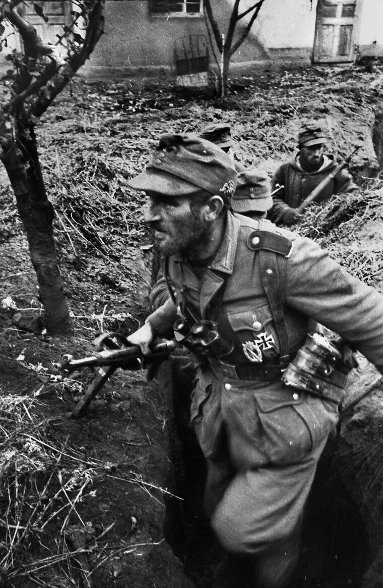 The strain of combat evident on his face, a German infantryman and his comrades move cautiously along a ditch on the Eastern Front. A total of 55 soldiers managed to escape Ternopil and make their way to the main German line.