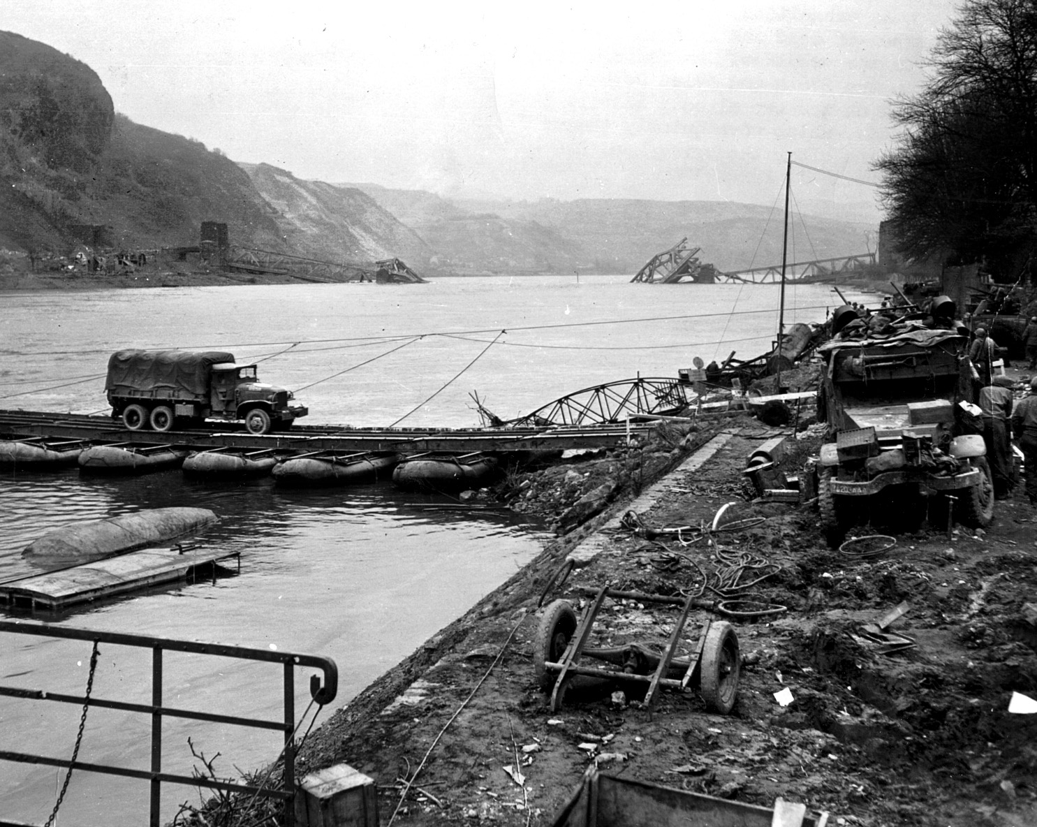 The remnants of the destroyed bridge are seen in the background of this photo depicting one of two pontoon bridges the Americans deployed to facilitate the movement of troops and equipment across the Rhine. 