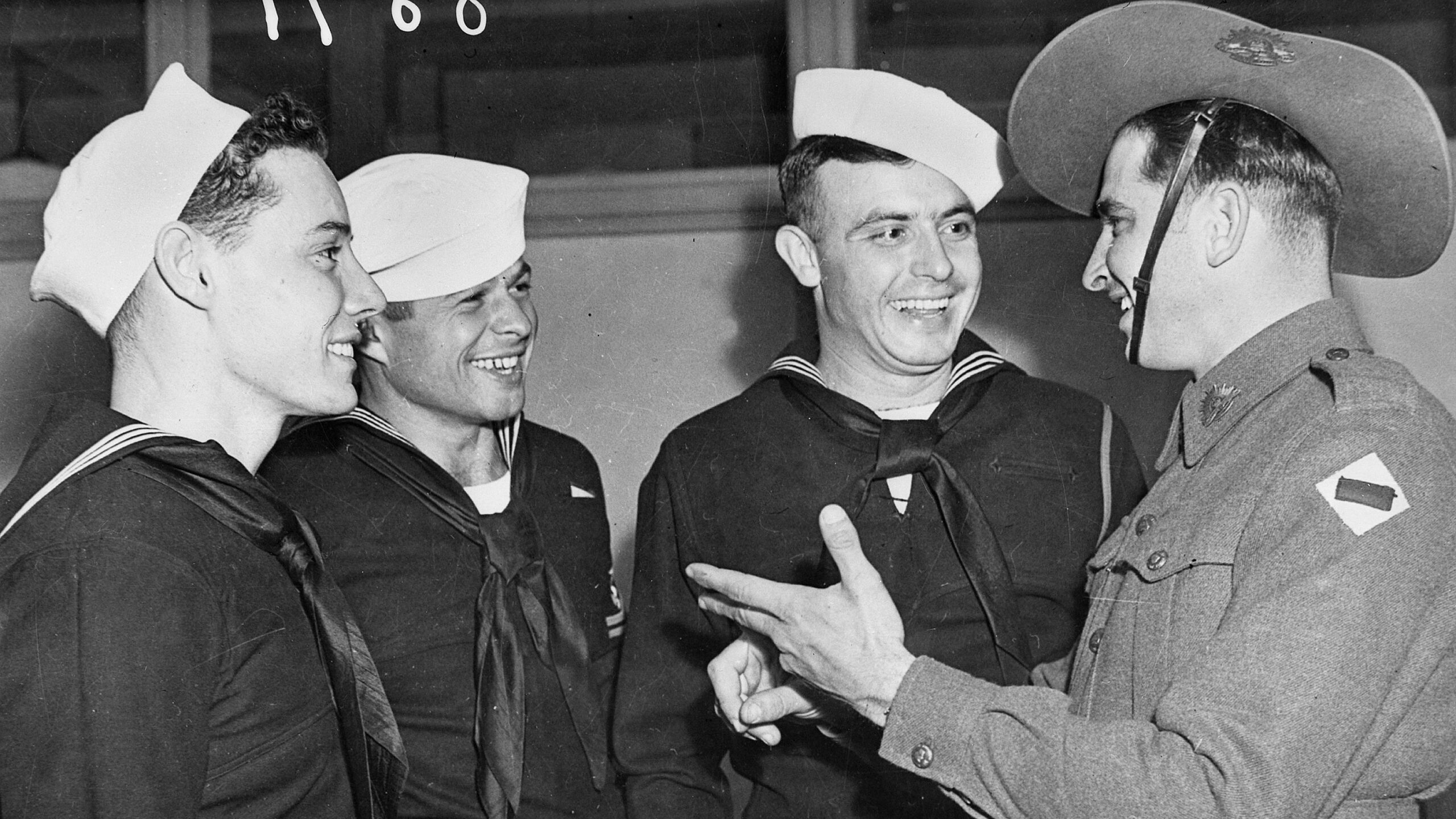 Australian Corporal G.E. Burns welcomes a trio of American sailors to Brisbane in a photo that has obviously been staged.