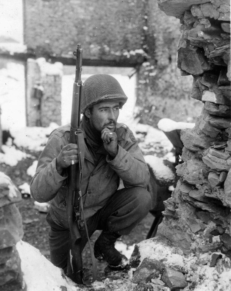 Looking for the nest of a German sniper in the Belgian town of Lutrebois, Sergeant Herbert S. Liman of the 134th Regiment, 25th Infantry Division watches for telltale movement.