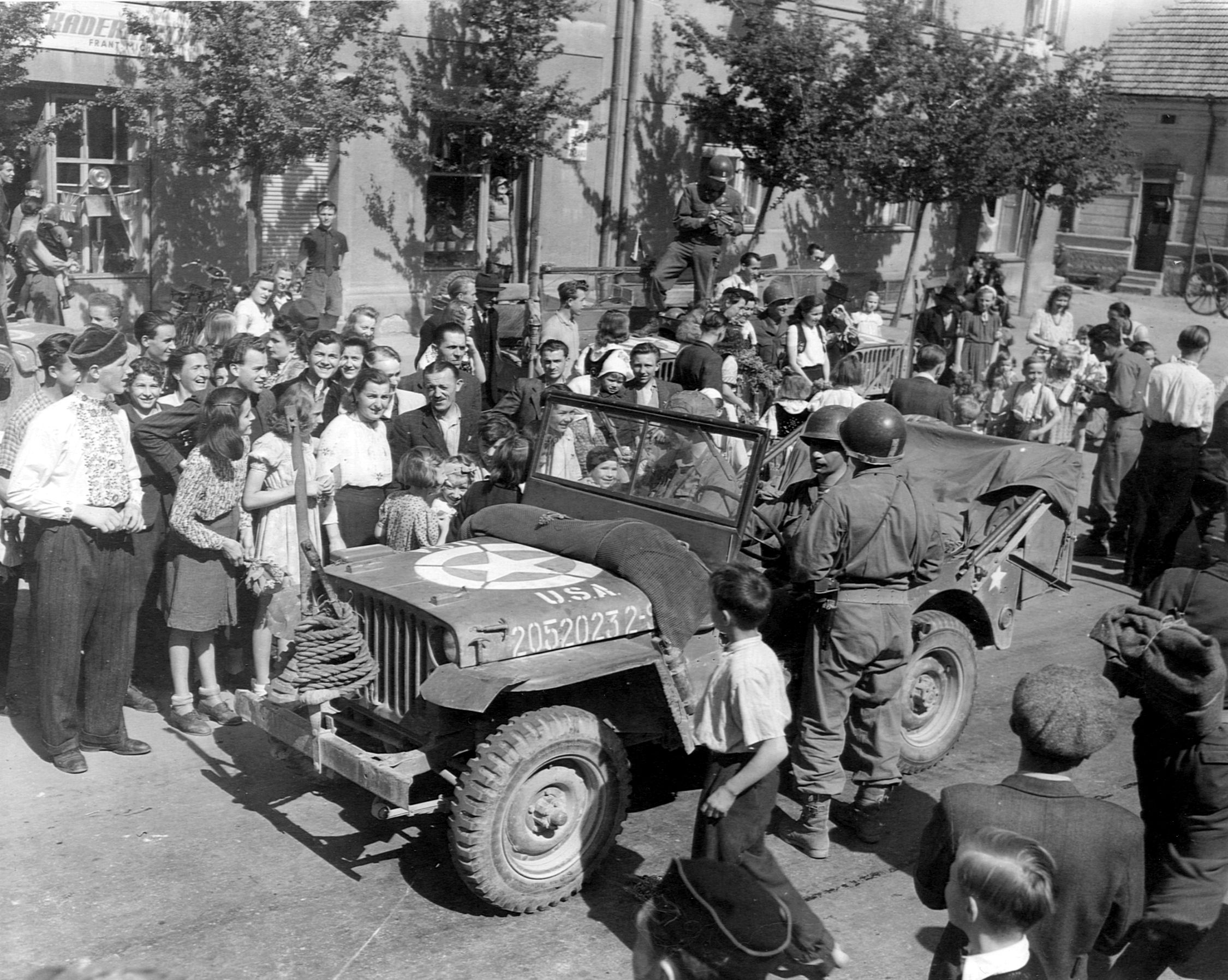 Czech civilians crowd around a U.S. Army jeep as American troops are welcomed into the liberated capital city of Prague on May 8, 1945.