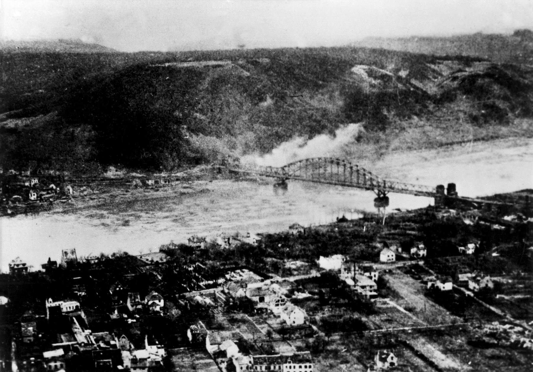 Plumes of smoke drift above the towers of the Ludendorff bridge as German artillery shells the area to disrupt the movement of American troops and supplies to the eastern bank. The Germans also launched air attacks in an effort to destroy the bridge. 