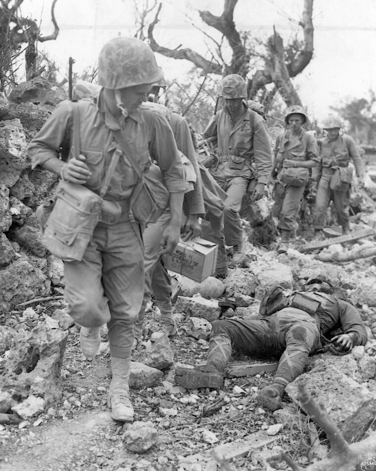 Pressing forward, U.S. Marines glance at the body of a dead Japanese soldier on May 24, 1945. At the time this photo was taken, another grueling month of fighting and dying remained before Okinawa was declared secure.