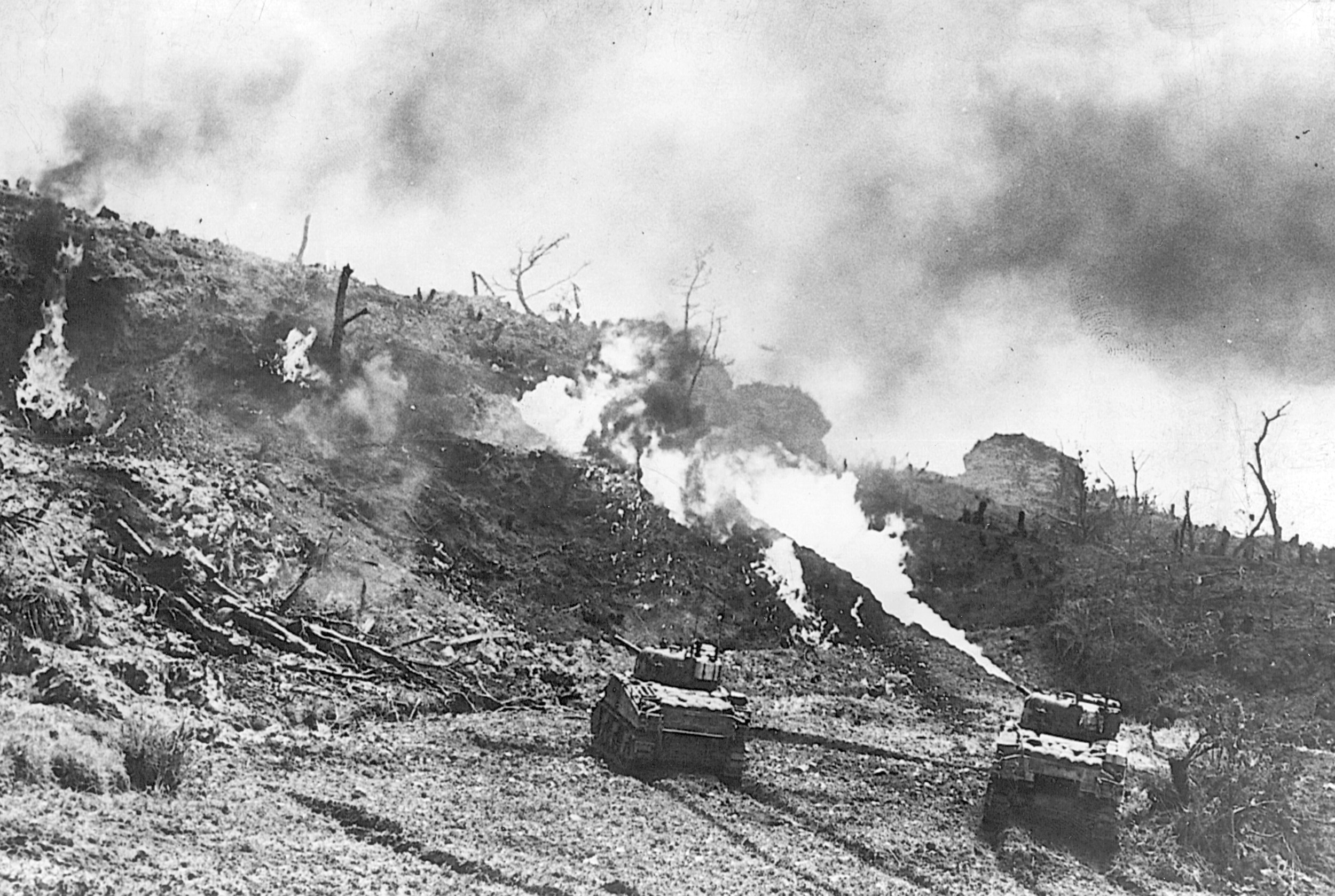 Tanks of the 7th Infantry Division, equipped with flamethrowers, spew fire into the openings of Japanese pillboxes and bunkers. The Japanese often fought to the death, and using such weapons was sometimes the only way to silence their guns.  