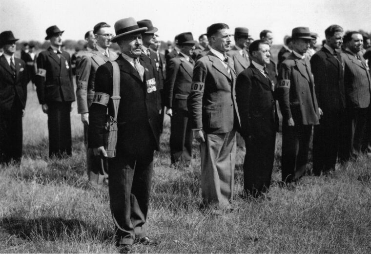 A group of British World War I veterans muster as Local Defense Volunteers during the dark days as Britain stands alone against the Nazis. General Claude Auchinleck led Southern Command as the British prepared for a German cross-Channel invasion that never materialized.