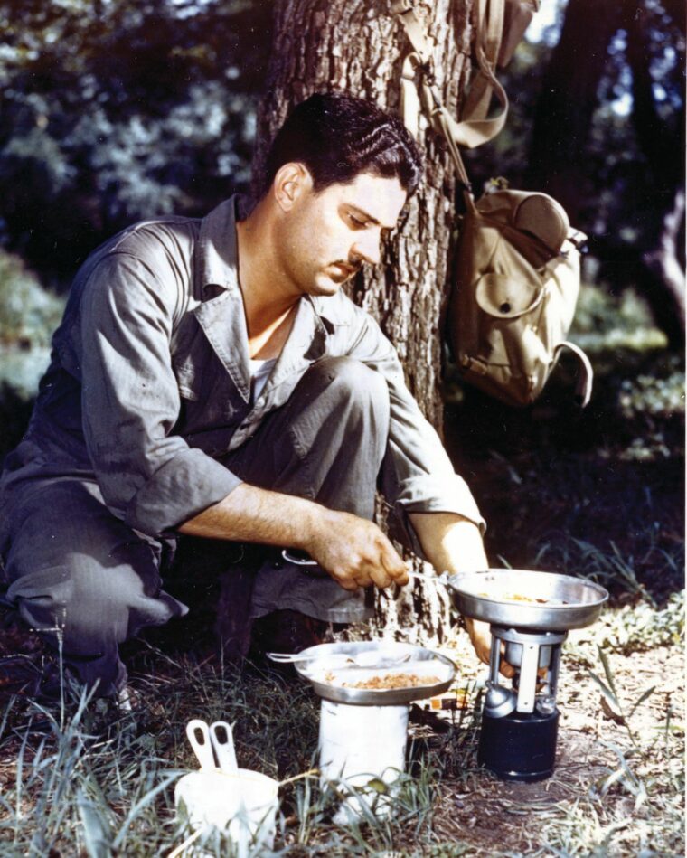 A trainee at Camp McClellen, Alabama, adjusts the flame on his portable stove. 