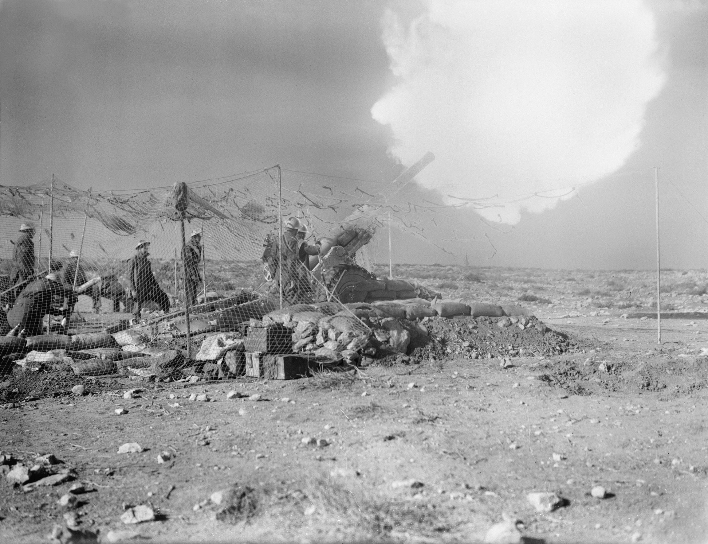 With a camouflage net draped above it, a British Bofors gun fires at Italian positions at Derna on February 1, 1941.