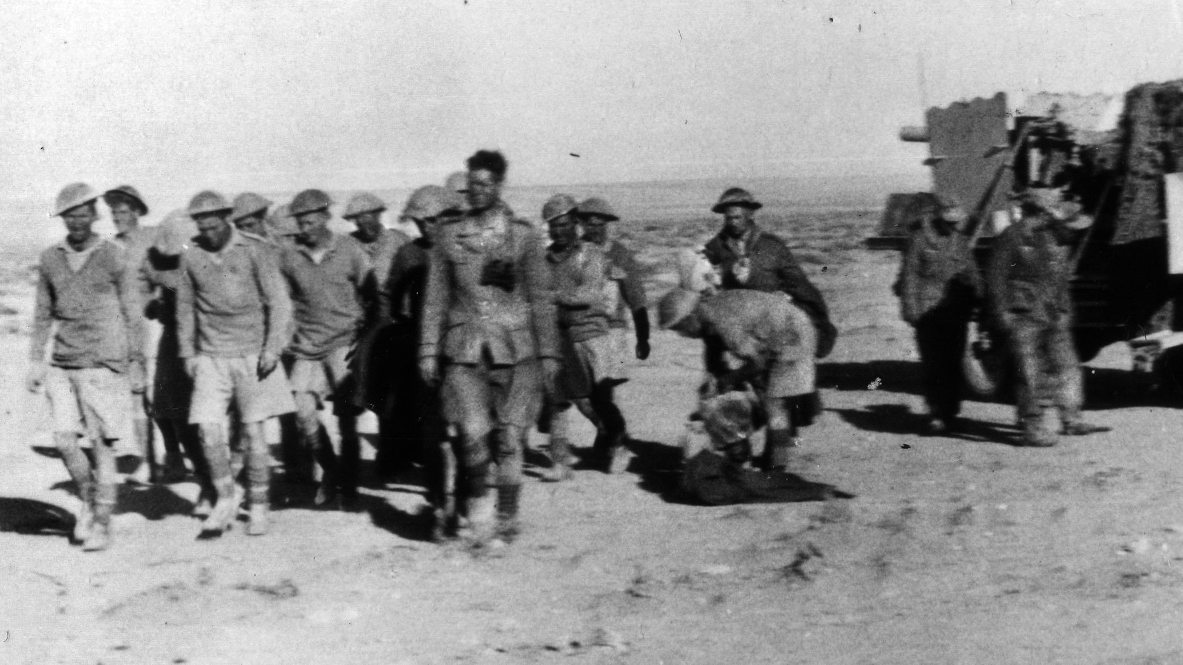 Several still wearing their distinctive helmets, a group of British soldiers taken prisoner following a defeat at the hands of the German Afrika Korps marches toward captivity. 