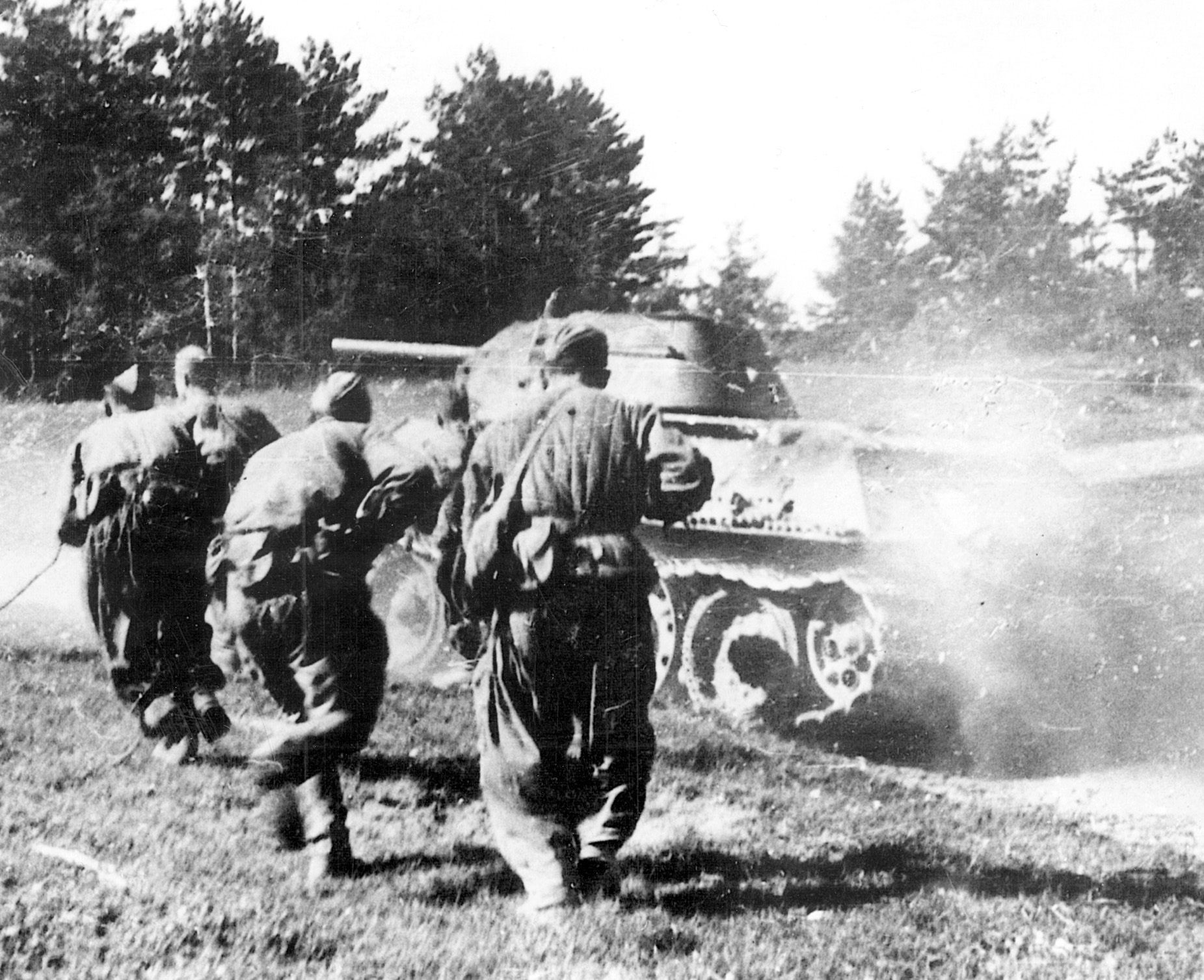 An advancing T-34 tank stirs up a cloud of summertime dust as Red Army soldiers crouch behind it. The Soviet armed forces mounted a devastating offensive in 1944, which carried them 
to the gates of Berlin.