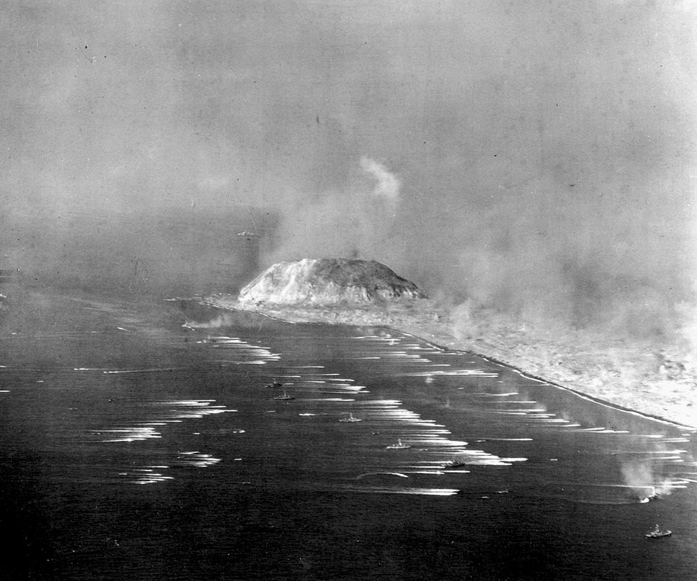 Dozens of U.S. landing craft head for the beaches at Iwo Jima. Mount Suribachi looms in the background.