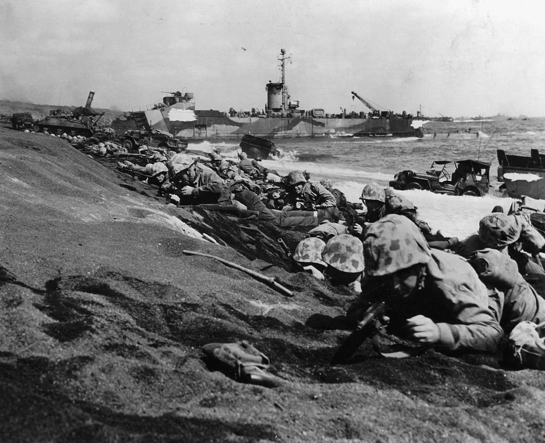 Marines in the 4th Division hug the loosely packed black volcanic sand mere moments before Japanese artillery and machine-gun fire erupts. 