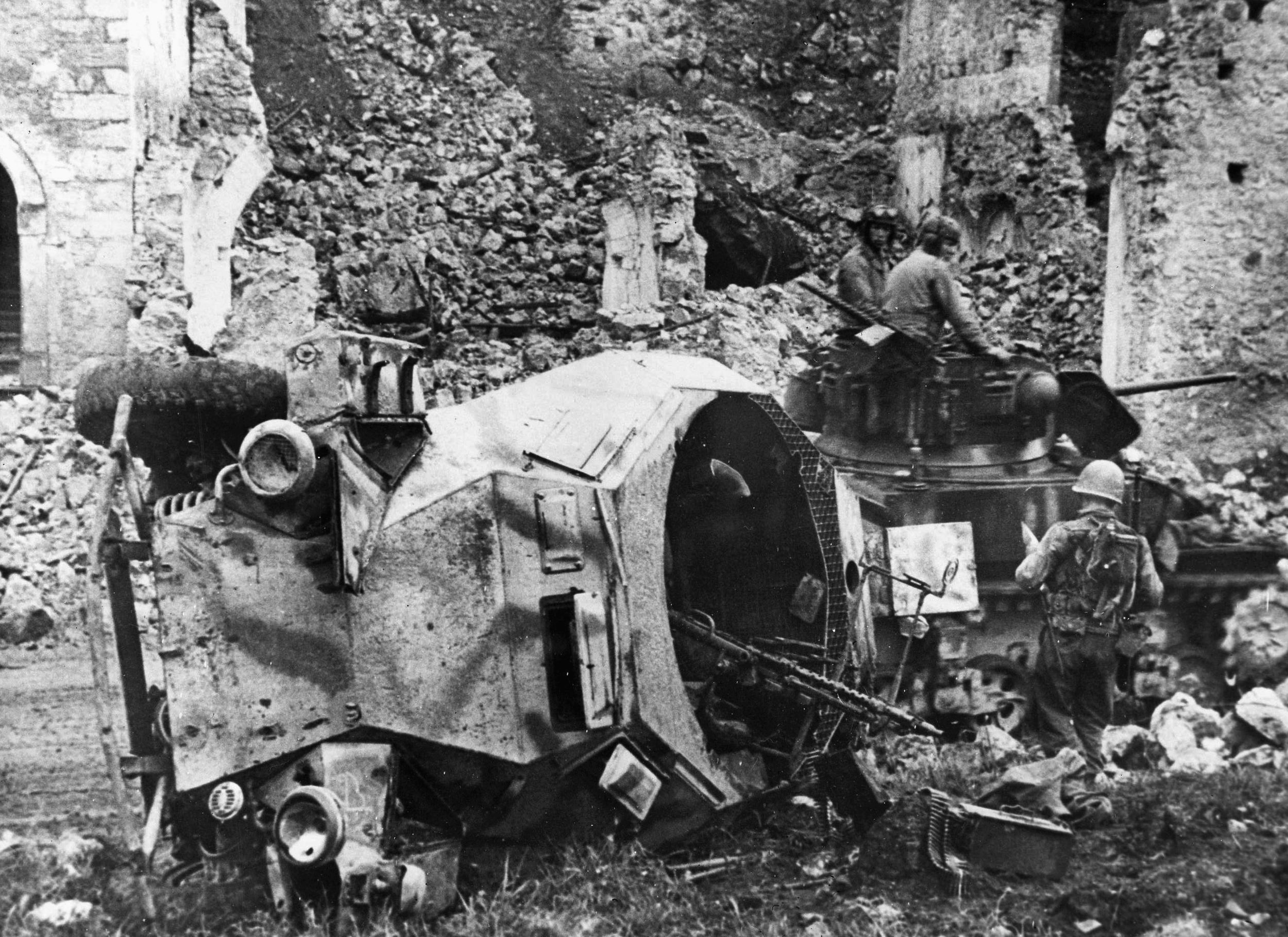 An American tank crew looks over a knocked-out German armored vehicle near Itri, Italy, in May 1944.