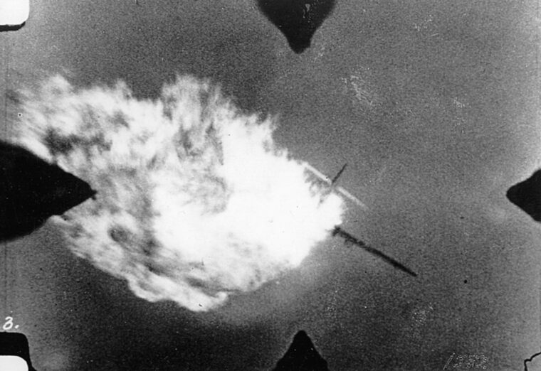 A Me-109 has its belly tanks set ablaze.